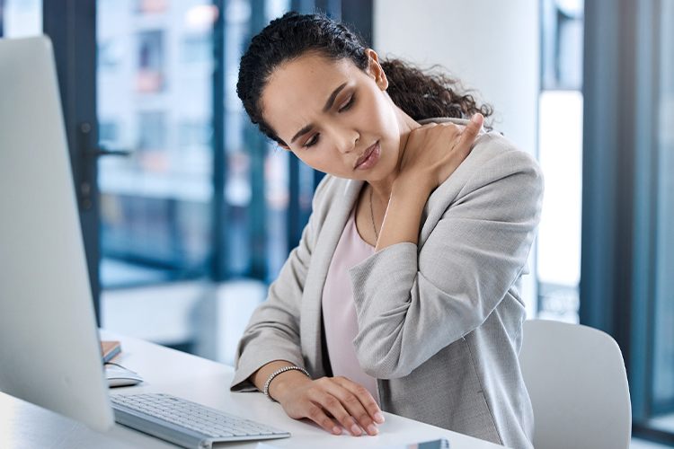 Woman with neck pain sitting at a desk using a computer