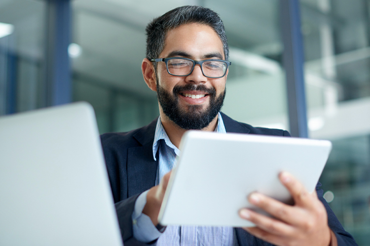Man using a digital tablet and laptop in an office