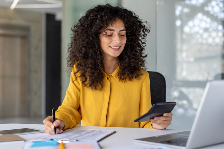 Woman using a calculator and pen in her office