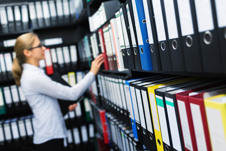 Woman filing folders in an archive room