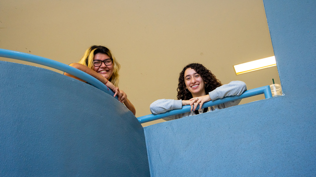 Two smilining students leaning over railing Two smilining students leaning over railing