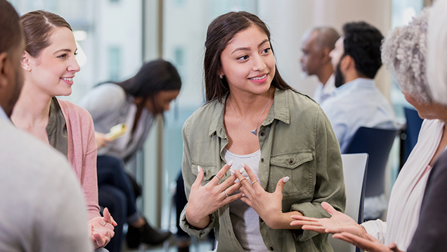 Student talking to a group of people during a meeting